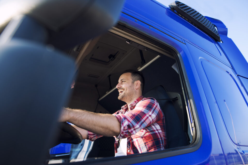 professional middle aged trucker cabin driving truck smiling